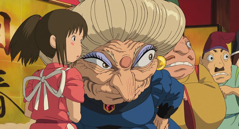 Yubaba talking to Chihiro while scowling to the side.