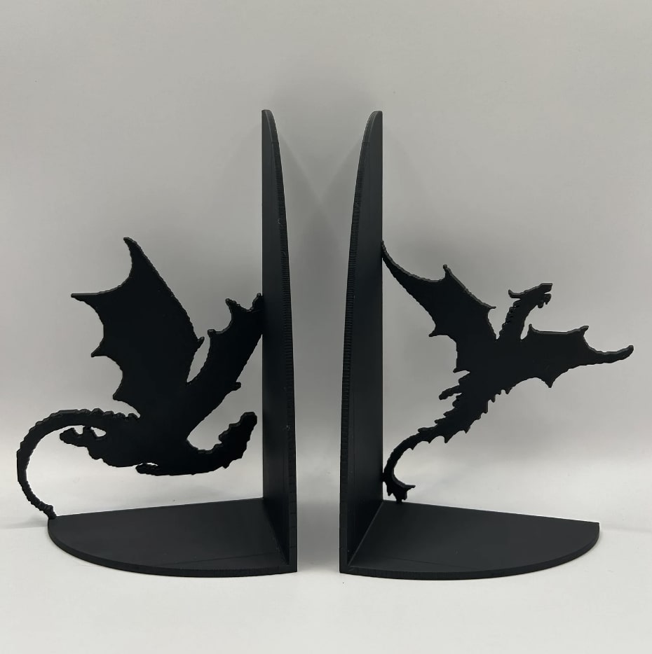 Black dragon bookends in different stages of flight. The one on the right is swooping down low and flying towards where the books would be, and the one on the left is soaring upwards away from where the books would be.