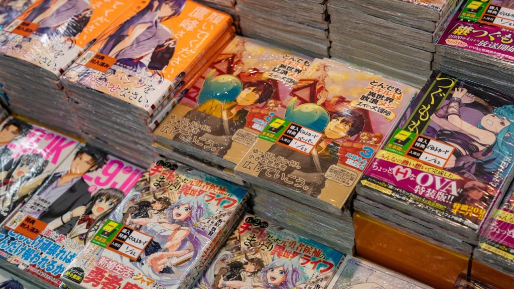 Stacks of colorful manga magazines stacked in rows. The covers include images of young women and young men with purple, blue, and black hair as well as large, colorful text.