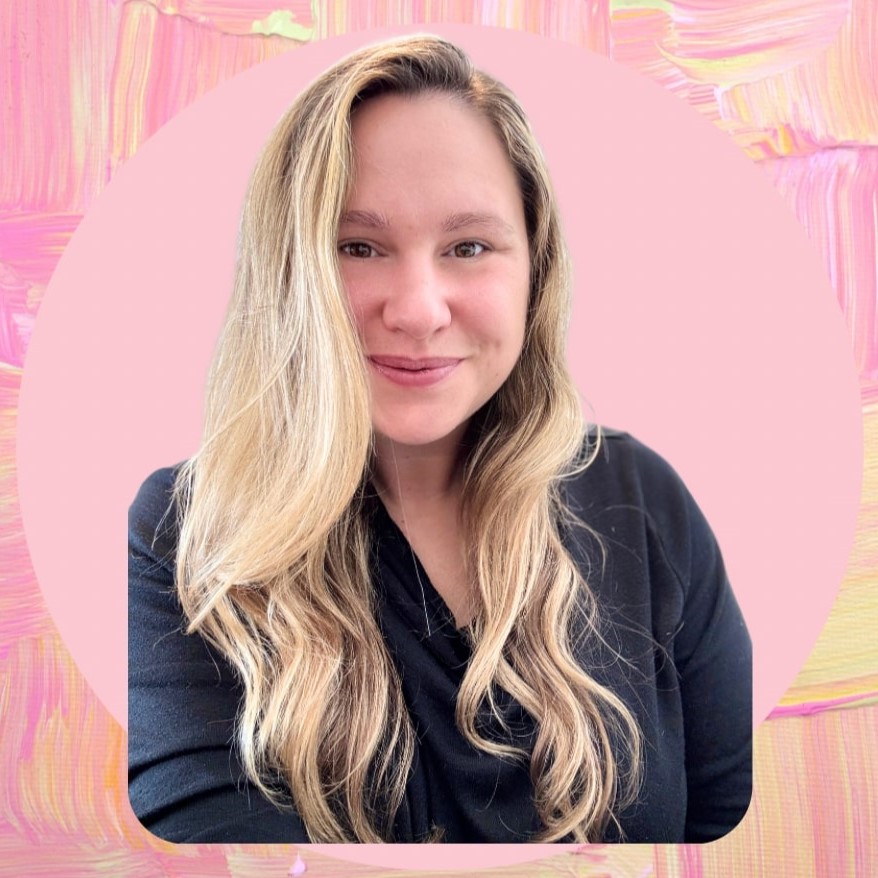 A white woman with long blond hair and a wearing dark blouse smiles at the viewer, against a pink and yellow background with painted brushstrokes.