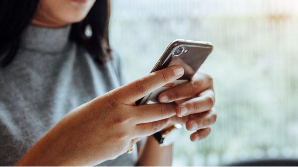 A photograph of a woman texting on a phone.