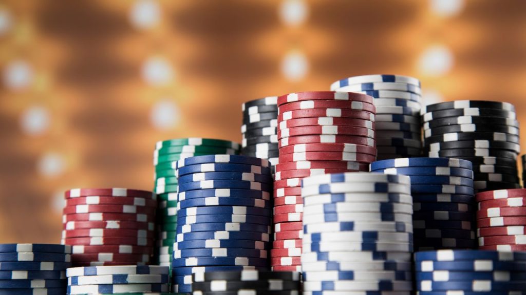 A stack of red, blue, white, and green poker chips against a brownish-yellow background.