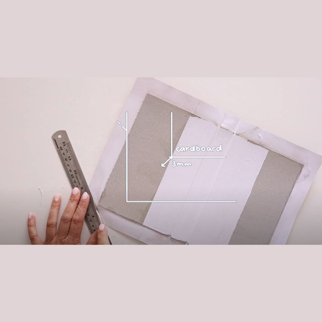 piece of cardboard with the words cardboard and three millimeter pointing to the corners to show how much space to leave.