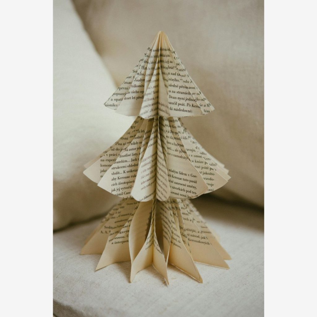 Book pages shaped into a Christmas Tree sitting on a light tan couch.