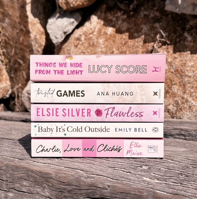 pink and white book spines on a wood log.