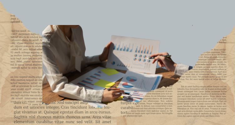 Two people work on graphs and charts among torn pages.