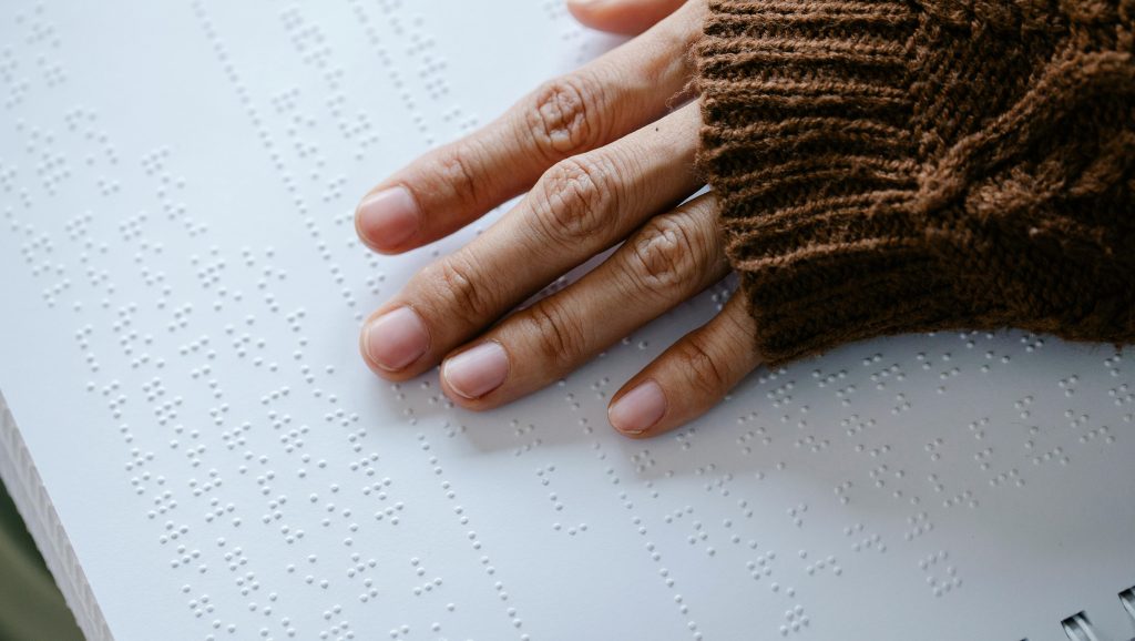 Hand feeling over braille on page.