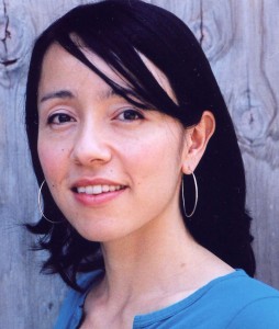A woman with short black hair and hoop earrings smiles.