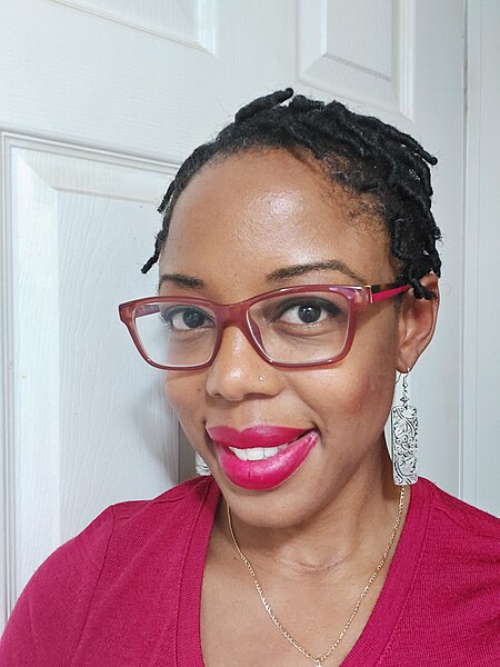 A woman with glasses smiles at the camera.