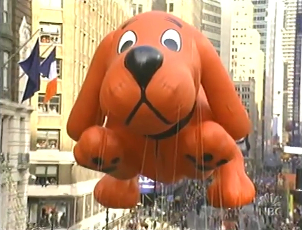 Parade balloon of Clifford the Big Red Dog being leg through New York city.