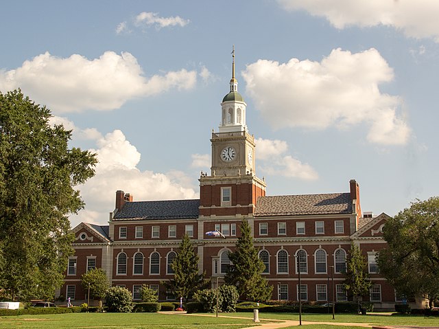 University building with clock tower on a cloudy sky.