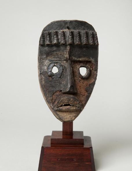 A face mask on a wooden pedestal.