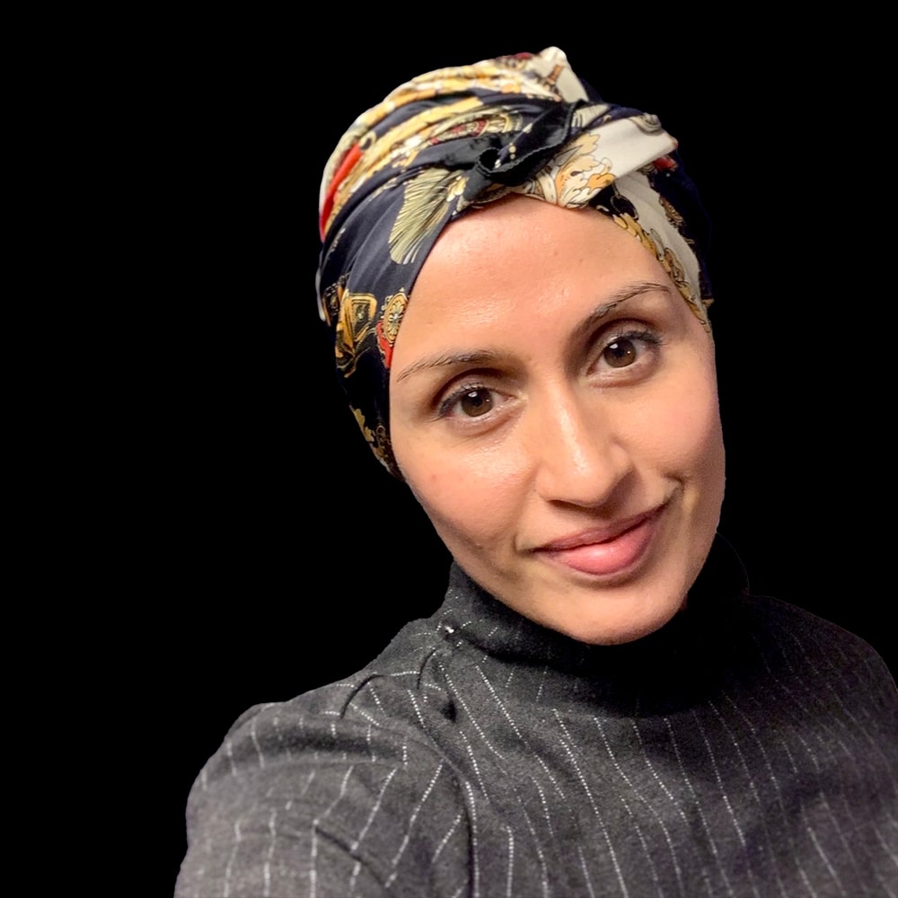 Photo of A. M. Dassu, a tan woman with a patterned headscarf and a grey turtleneck.