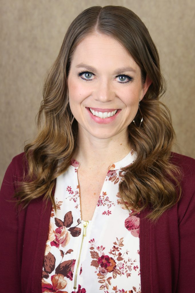 Photo of Lindsay Kemeny, a light-skinned woman with brown hair and a floral blouse.