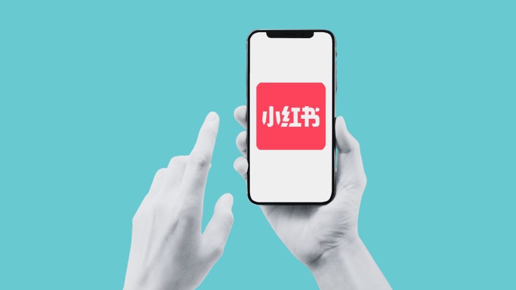 A hand holds a phone that is opening RedNote