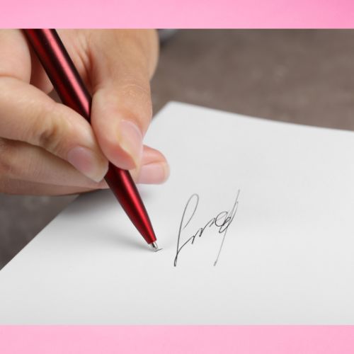 A hand signing a sheet of paper against a pink background.