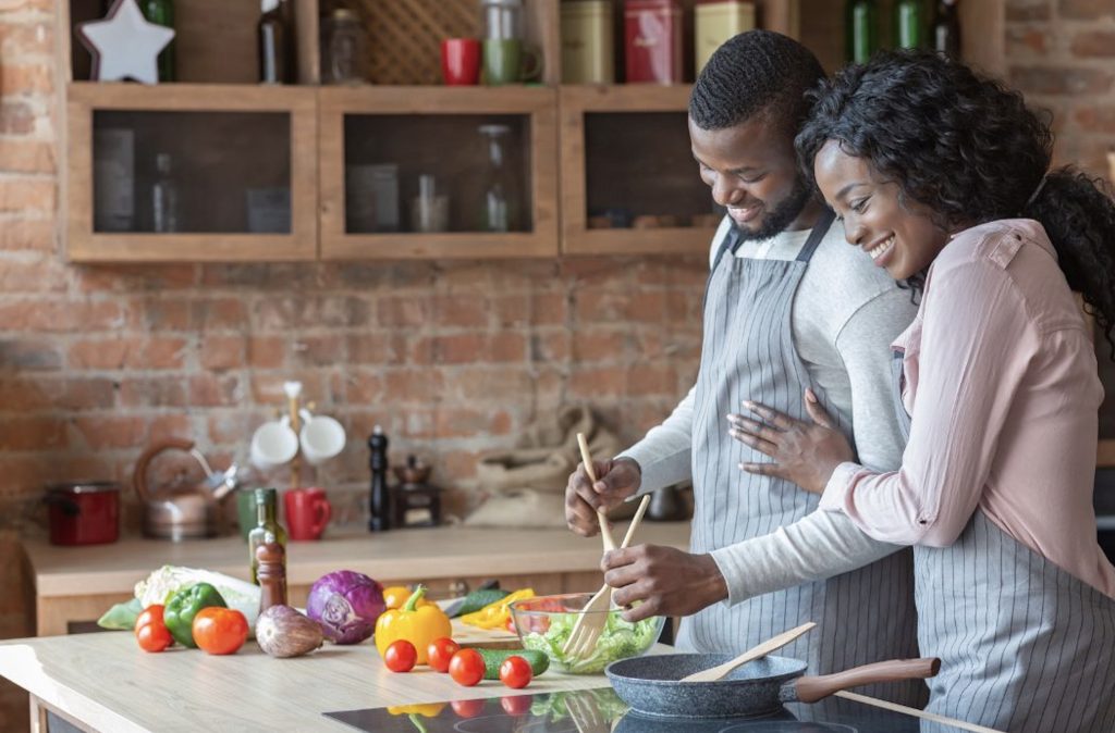 Happy couple preparing food together in a rustic kitchen.