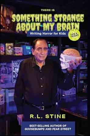 R.L. Stine in black, holding up a skull with a brain in it. He's standing before a wall of media featuring his works. The title of this book is There's Something Strange About My Brain: Writing Horror for Kids.