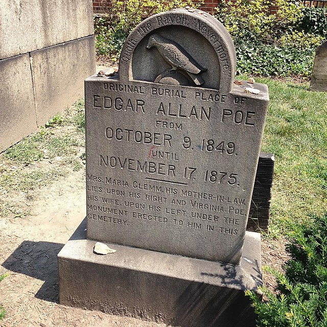 A picture of his grave in Baltimore, Maryland. A gray headstone that displays his name, date of birth and date of death, and an epitaph etched underneath.