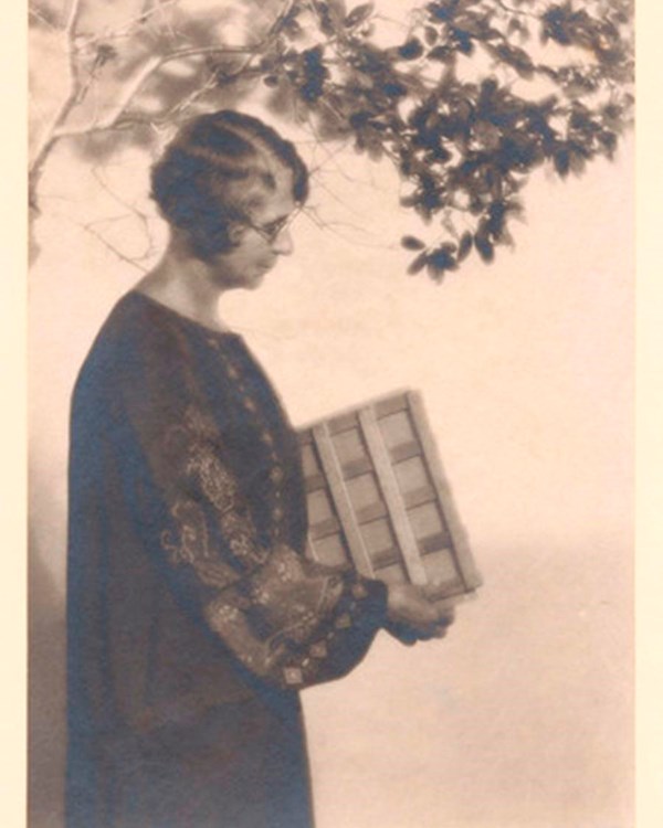 Ynes Mexia looking at a box she's holding while walking outside