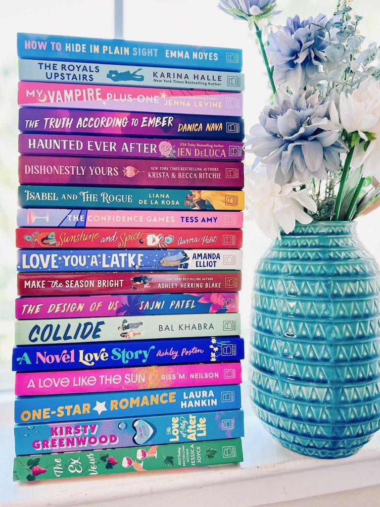 stack of pink, blue, and pink books next to a blue vase with blue and white flowers