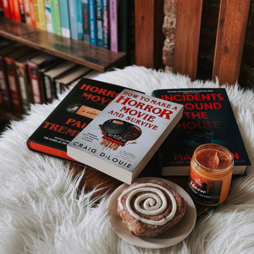 Hannah's book recs including a Craig DiLouie book next toa cinnamon roll and a candle