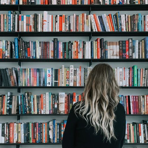 Hannah looking at her full bookshelves with her back to the camera.