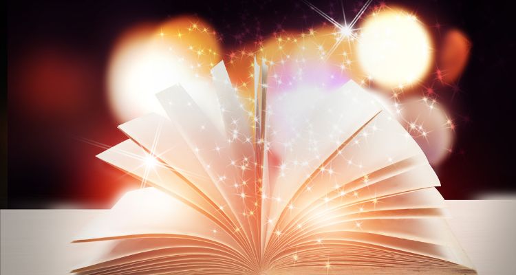 A picture of a book open and flat with shiny glitter and sparkles coming out of the pages against a faded orange light