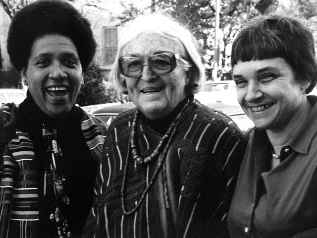 Audre Lorde posing in black and white photograph with friends.