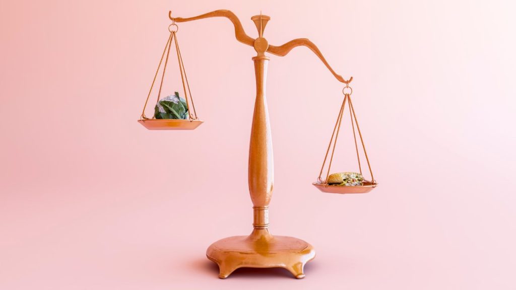 A weighted scale with one side leaning to the right. The scale is against a pink background.