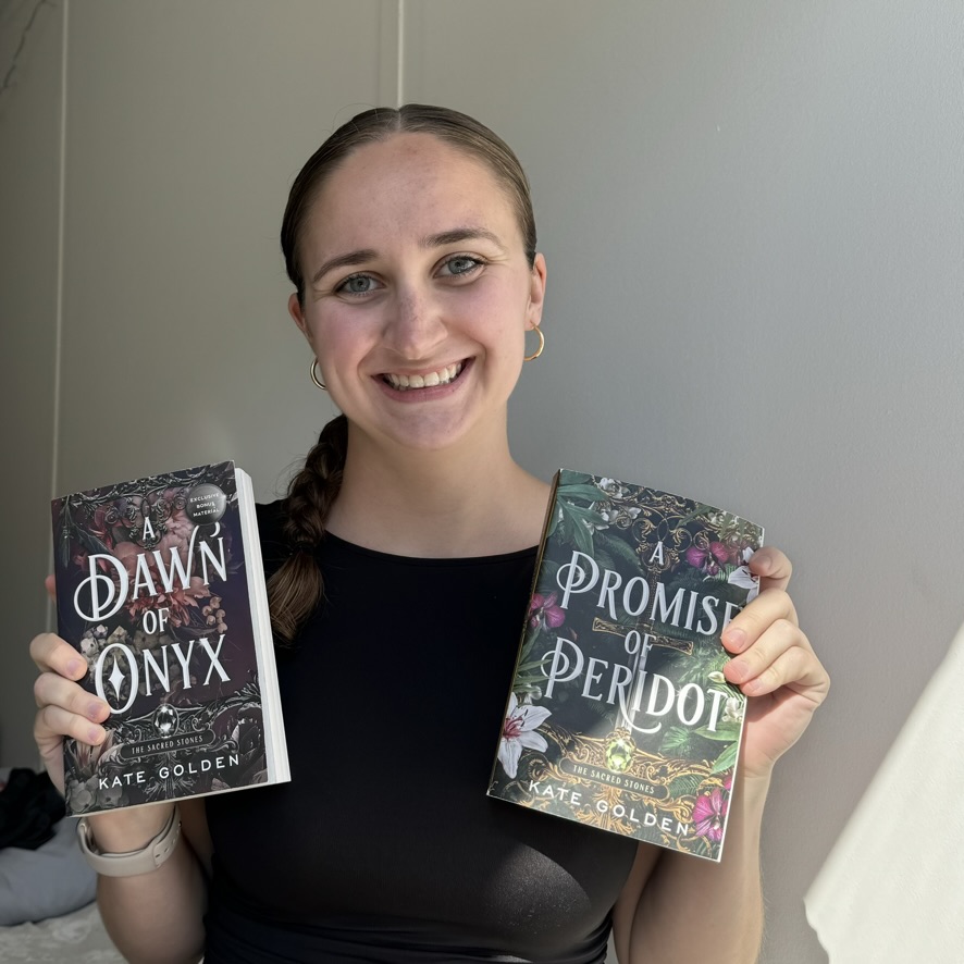 Kerryann holding up two books, A Dawn of Onyx and A Promise of Peridot, both by Kate Golden.