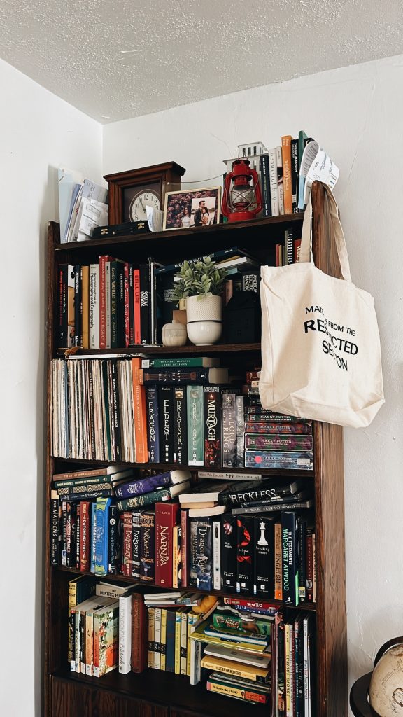 A crowded bookshelf in the corner of a room.