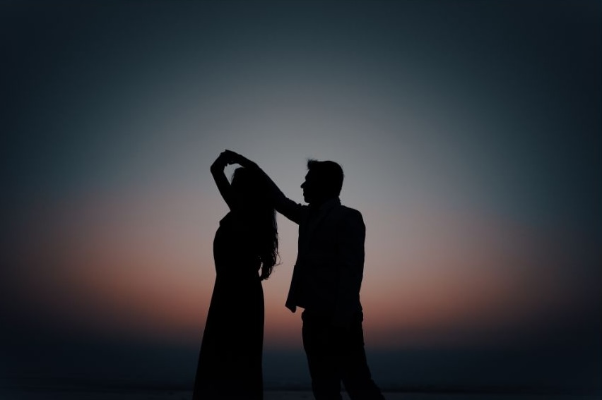 A photo of a silhoette of a couple dancing during sunset.