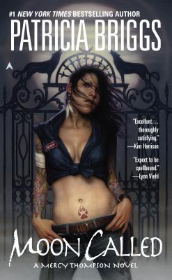 Moon Called book cover by Patricia Briggs, shows a tattooed Mercy in a blue work shirt standing in front of an ornate gate at night.