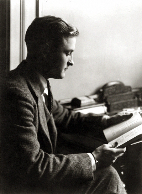 In black and white, F. Scott Fitzgerald sits and reads a book. He wears a suit.