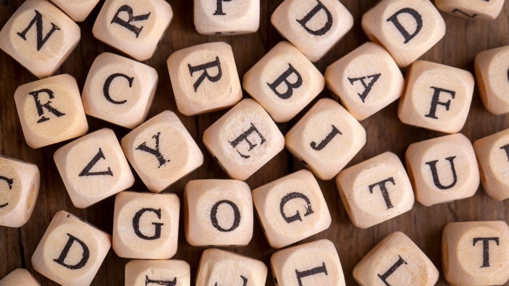 A wooden tabletop. Multiple wooden cubes with different letters carved on them.