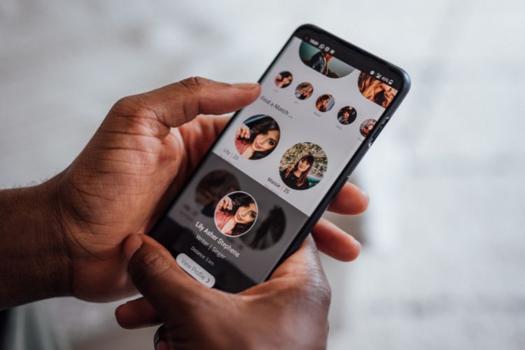A phone in hands looking at an online dating profile.
