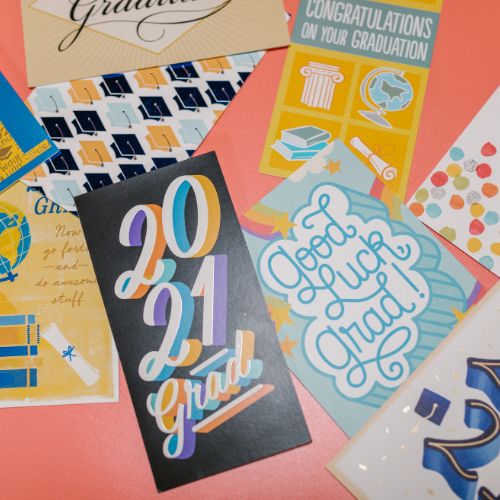 Various greeting cards against the salmon pink background saying congratulations for graduating.