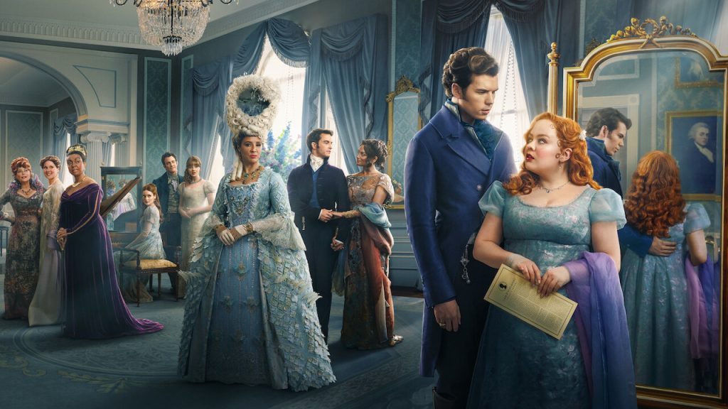 Elegantly dressed characters in a grand ballroom, with Penelope holding a letter, reflecting in a mirror, as she speaks to Colin dressed in a dark blue suit.
