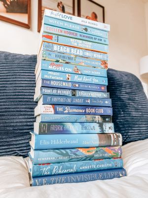 A stack of blue books with their spines and titles facing the viewer, resting on a white cushion with a blue cushion in the background.