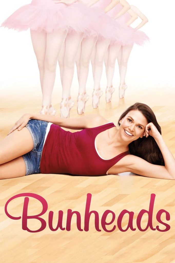 A wooden dance floor fading into a white background. A woman with long brown hair, a red tank top, and jean shorts lies across the floor with. her head resting on her hand and smiles. Behind her are the legs of six ballerinas wearing pink tutus and pointe shoes. Bunheads is written in red lettering.