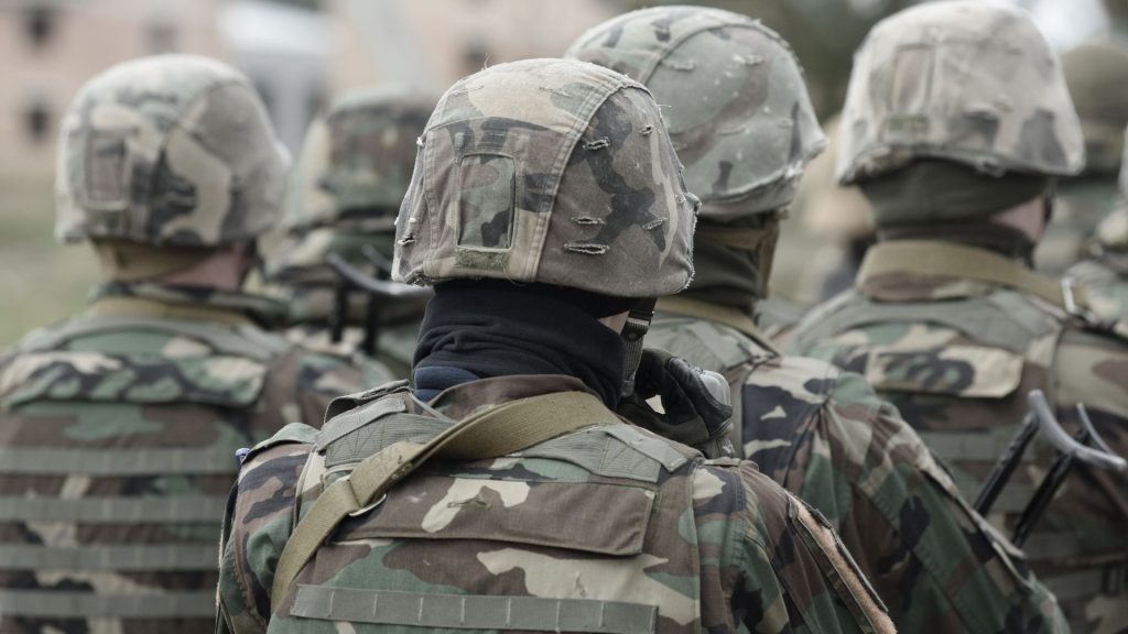 Soldiers wearing camouflage uniforms and helmets standing in a group.