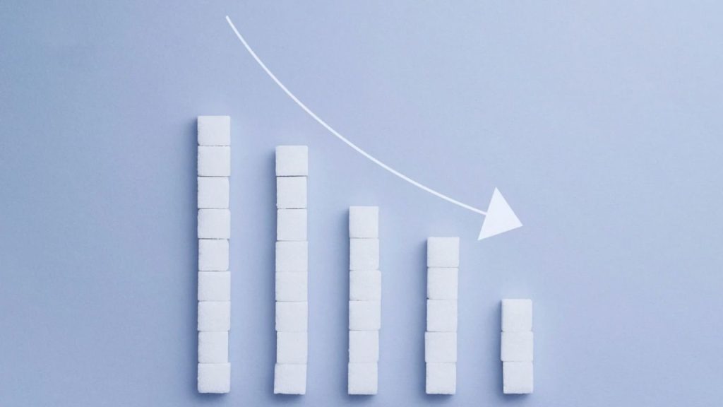 An image of a white bar graph declining, showing 5 columns and a white arrow tilting downward to show the decline, with a light blue background.
