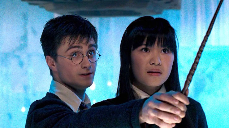A still shot from the Harry Potter film of Harry and Cho Chang, Harry on the right holding out his wand in front of the camera next to a worried looking Cho Chang