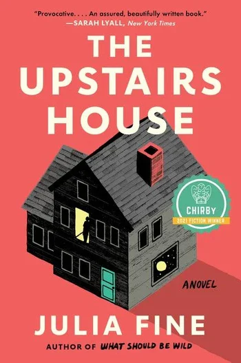 The Upstairs House by Julia Fine book cover. Centered is a gray home with two stories and a window in the roof. A person stands in the second story, with a yellow light shining in the hallway. The background of the cover is a chimney-red, which matches the chimney of the house.