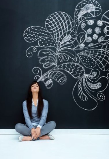 A woman sitting cross-legged on the ground. Large, swirling shapes, some with lines running through them, squiggles, or large dots, sprouting from her head and expanding.