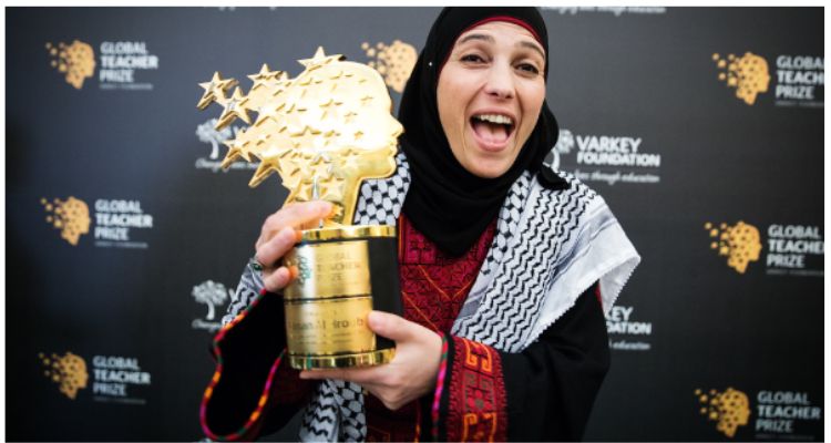 Hanan Al Hroub smiling widely and displaying her golden Global Teacher Prize at the award ceremony.