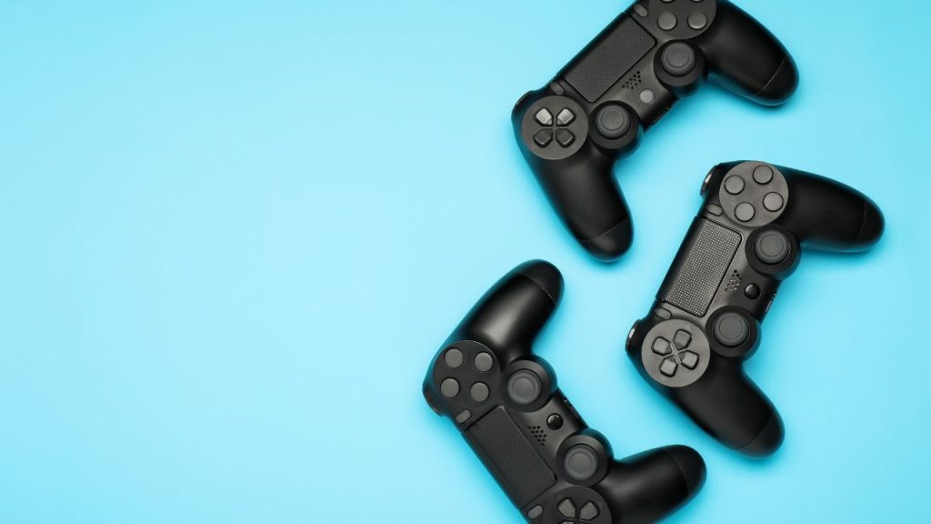 Three black video game controllers on an light blue background.