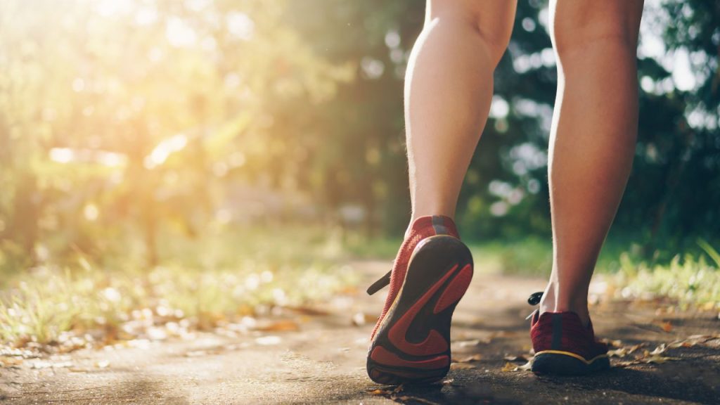 A person's legs walking on a trail outside.