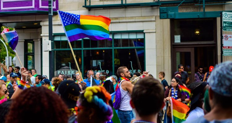 Pride parade in front of a chicago shop called paired. Lot of people with Pride flags are in the streets.